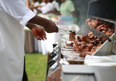 person in white shirt grilling meat